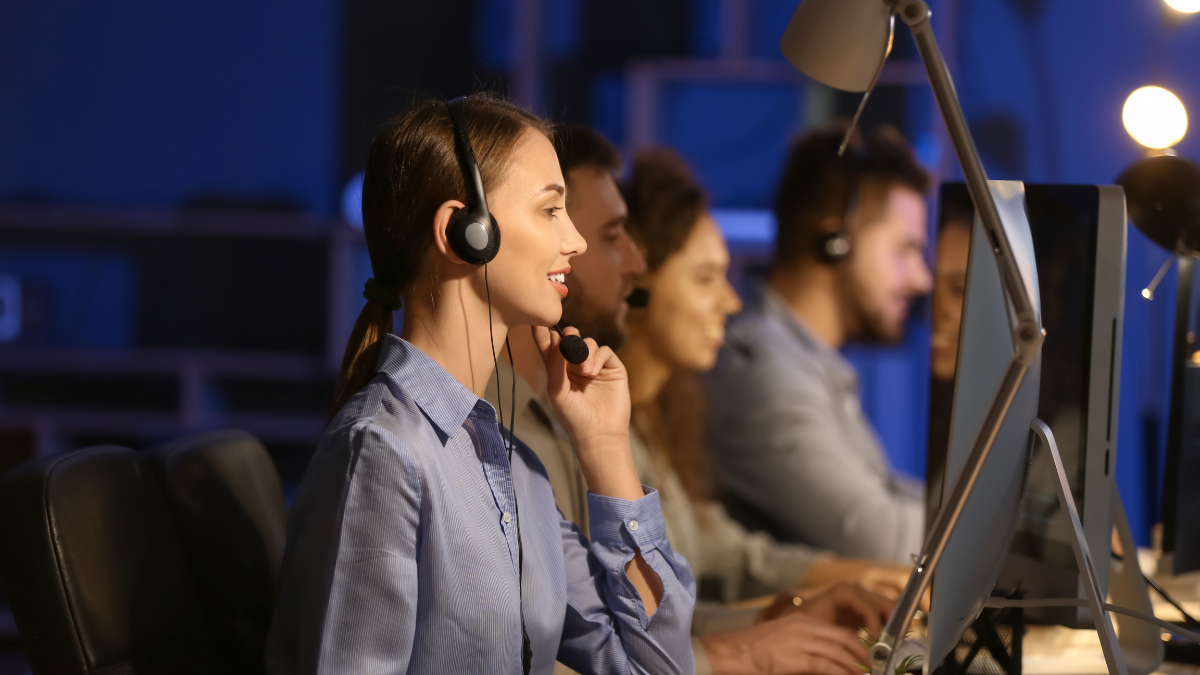 Female call center agent wearing a headset while working in a 24/7 live answering service office